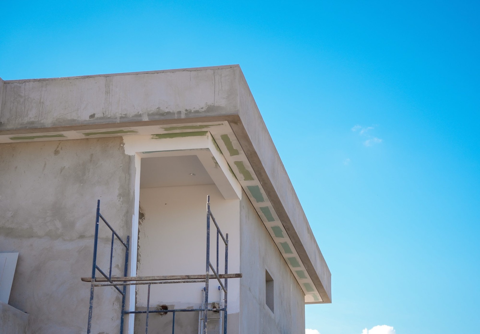 Residência em obra, com estrutura de concreto, forro em preparação e andaime, sob céu azul